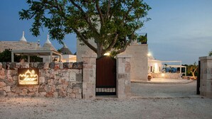 Un muro de piedra con una puerta de madera y un letrero de neón para "Lococo Trulli Experience".