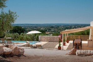 A patio with a pool, outdoor furniture, and a view of the landscape.