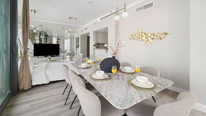 A modern dining area with a marble table, white plates, and glasses of orange juice. - FIRST CLASS | 3BR | Burj Khalifa & Fountain view (Downtown)