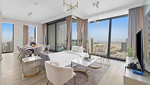 A modern hotel room with a large bed, a dining area, and a view of the cityscape. - FIRST CLASS | 3BR | Burj Khalifa & Fountain view (Downtown)