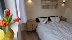 A bedroom with a bed, bedside tables, a wall-mounted light, and a window with curtains. - Unique and modern apartment with designer bathroom and terrace (Petting)
