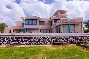 A modern two-story house with a stone wall, multiple windows, and a flat roof.