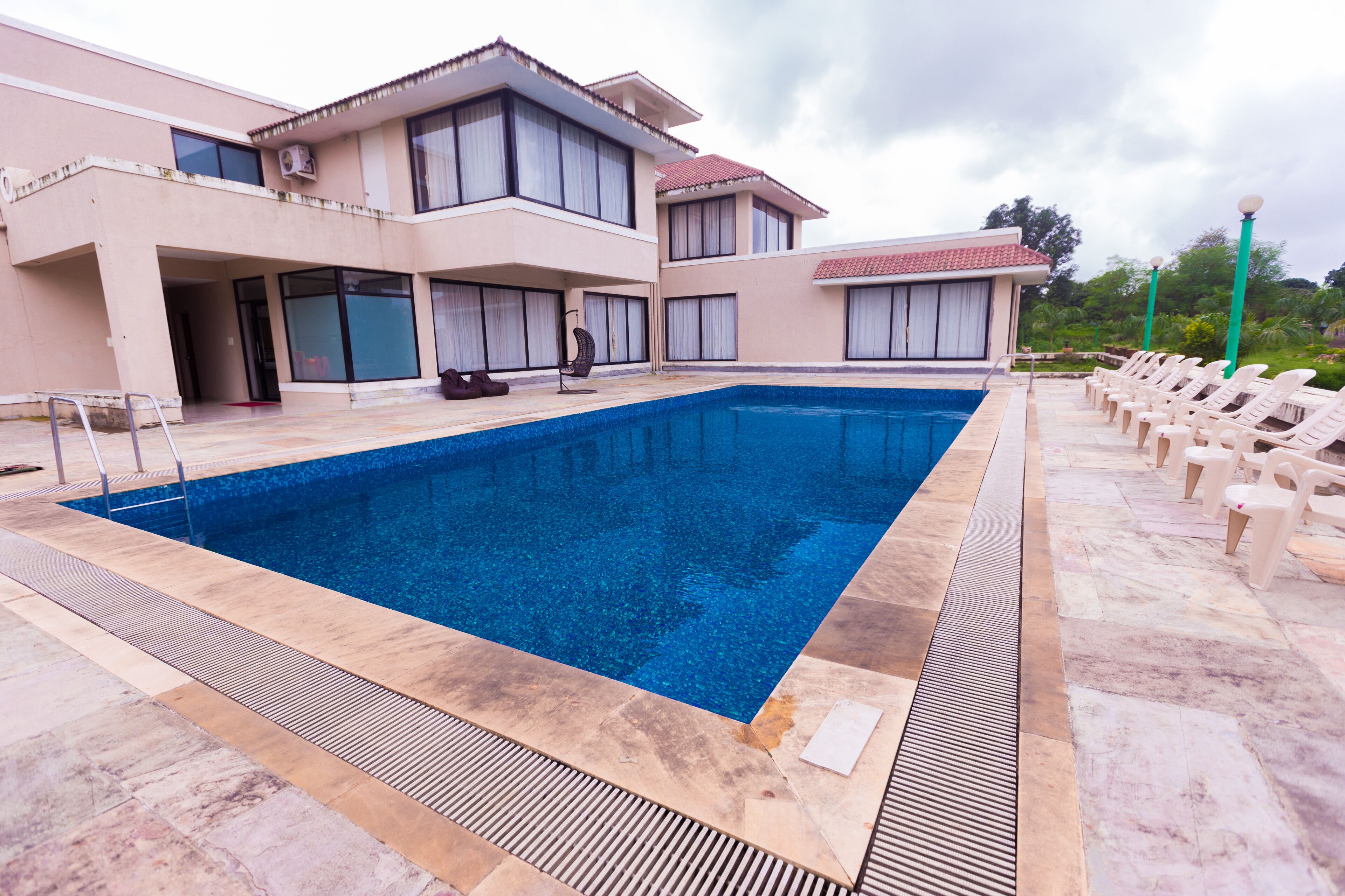 A swimming pool with lounge chairs and a building with multiple balconies.