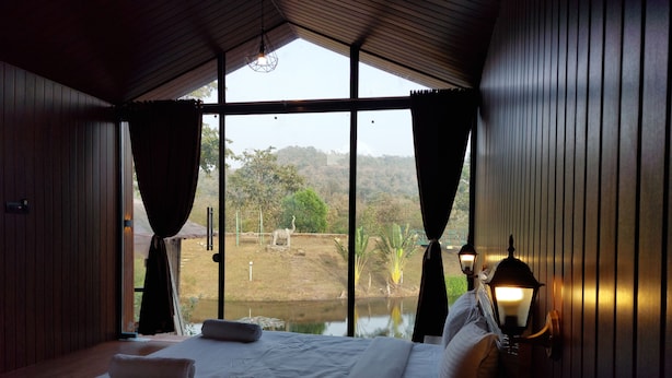 Un dormitorio con una cama grande, cortinas, vistas a un paisaje y una lámpara.
