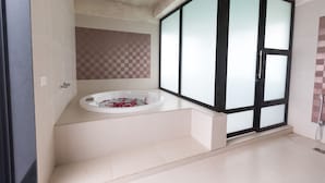 Un baño moderno con una bañera independiente, un amplio ventanal con vidrio satinado y un revestimiento de azulejos a cuadros.