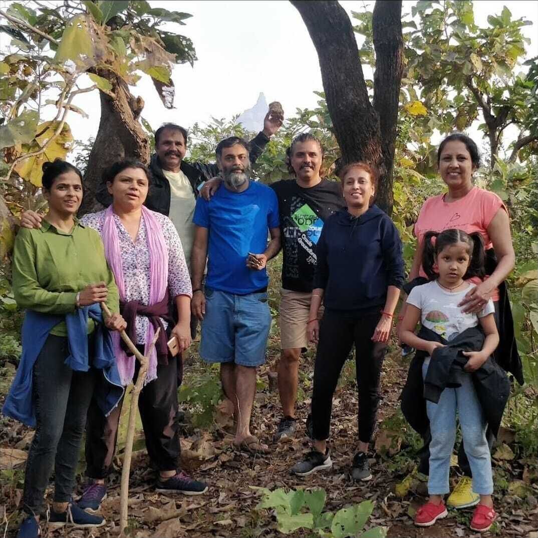 A group of people standing outdoors with trees and foliage in the background.