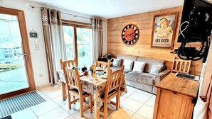 Ein gemütliches Zimmer mit Esstisch, Stühlen, einer Couch und einem Fernseher.