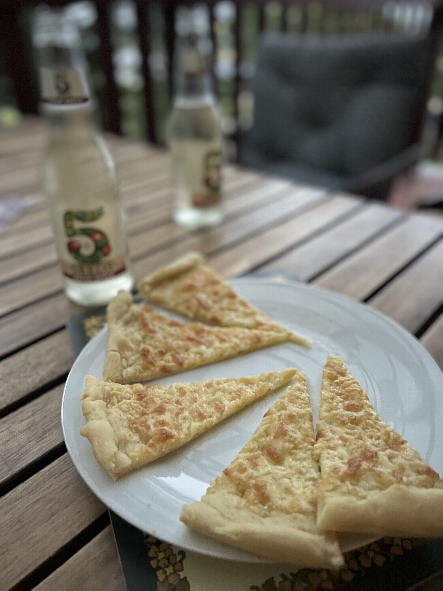 A plate with three slices of pizza on a wooden table.