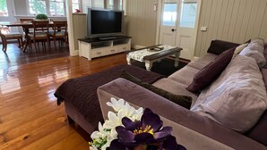 A living room with a sofa, a TV, and a dining area with chairs and a table. - Childers charmer - with aircon, WIFI and modern luxuries (Childers)