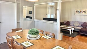 A dining area with a wooden table, chairs, a central potted plant, and a hanging light fixture. - Childers charmer - with aircon, WIFI and modern luxuries (Childers)