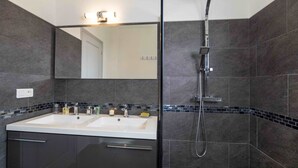 Een moderne badkamer met een dubbele wastafel, een grote spiegel en een douche.