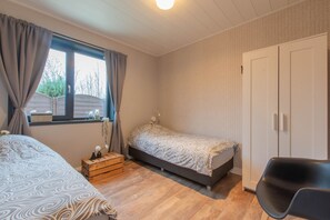 Cozy bedroom with a single bed, wooden chest of drawers, and a comfortable chair.