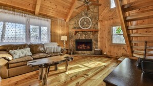 A log cabin interior with a stone fireplace, wooden ceiling, and a cozy living area with a sofa and coffee table. - A Blue Ridge Mason Jar | Blue Ridge, GA (Blue Ridge)