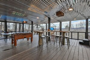 An indoor space with a wooden floor, a foosball table, and a bar area with stools.