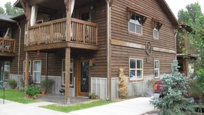 Un bâtiment en bois à deux étages, doté d’un balcon à l’étage supérieur, d’une porte d’entrée et d’un petit porche.