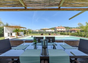 A poolside dining area with outdoor seating and a view of a swimming pool. - Comfortable villa with a private pool (Marina di Ascea)
