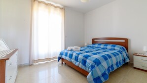 A bedroom with a bed, a wooden desk, a chair, a nightstand, and a window with curtains. - Comfortable villa with private swimming pool (Marina di Ascea)