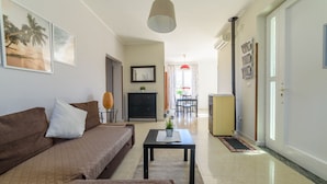 A living room with a sofa, a coffee table, and a TV. There is a dining area in the background with a table and chairs. - Comfortable villa with private swimming pool (Marina di Ascea)