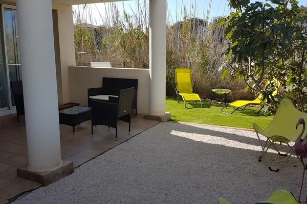 Extérieur avec terrasse abritée et jardin arboré.