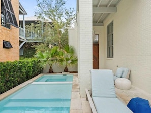 A swimming pool with lounge chairs and a brick wall.