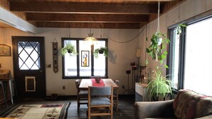 A cozy dining area with a wooden table and chairs, a patterned rug, and hanging plants.