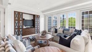 A spacious living room with a large window, a wooden entertainment unit, and a comfortable seating area.