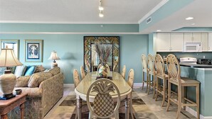 Un comedor con una mesa de vidrio rodeada de sillas, un sofá y una lámpara.
