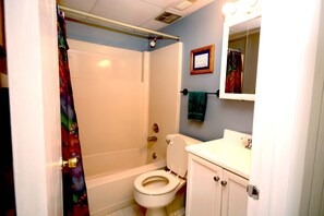 A bathroom with a shower, toilet, sink, and mirror. - One-bedroom and one and a half bath condo on ocean block! (Ocean City)