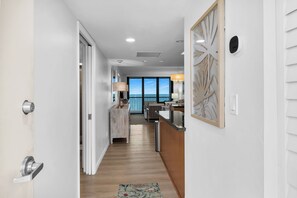 A hallway leading to a balcony with a view, a kitchen area with a counter, and a dining area with a table and chairs. - 2 Bed South End Beachfront Condo at Popular Seawinds (Marco Island)