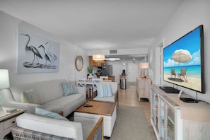 Ett modernt vardagsrum med en soffa, ett soffbord och en tv-skärm som visar en strandvy.