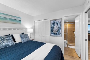 Ein Hotelzimmer mit Bett, einem Gemälde, einem Kleiderschrank und einem Badezimmer.