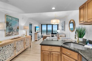 A spacious kitchen with a large island, wooden cabinets, and a view to the outside. - 2 Bed South End Beachfront Condo at Popular Seawinds (Marco Island)