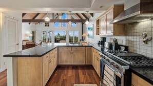 A spacious kitchen with wooden cabinets, a large island, and a stainless steel stove.