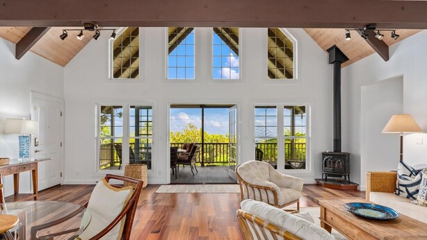A spacious living area with high ceilings, large windows, and a fireplace.