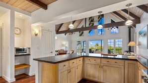 A spacious kitchen with wooden cabinets, a large island, and pendant lighting.