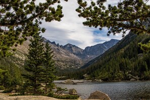 Paesaggio montuoso con un lago, circondato da fitti boschi e terreno roccioso.