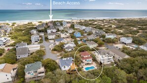 Vue aérienne d’un quartier résidentiel avec des maisons, un accès à la plage et une piscine.