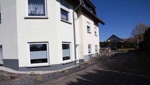 Une maison moderne à deux étages, dotée d’une allée pavée et d’un petit jardin.