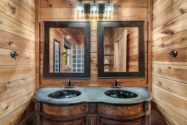 A wooden bathroom with two sinks, large mirrors, and a light fixture above.