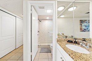 A modern bathroom with a white vanity, a large mirror, a bathtub, and a shower.