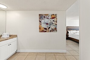 Une salle de bain avec un lavabo blanc, un plan de toilette et un porte-serviettes.