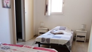 A bedroom with two beds, a window, and a door. - Vacation home 200 m from the beach (VALRAS PLAGE)