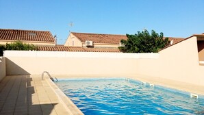 A swimming pool with tiled deck, surrounded by buildings with terracotta roofs and white walls. - Vacation home 200 m from the beach (VALRAS PLAGE)