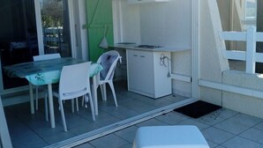 A small kitchen area with a table and chairs, a refrigerator, and a green door. - Vacation home 200 m from the beach (VALRAS PLAGE)