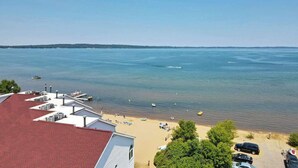 A coastal view with a beach, boats, and a parking area.