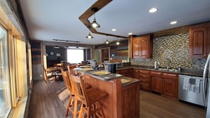 A spacious kitchen with wooden cabinets, a large island with bar stools, and a built-in oven.