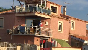 Un immeuble de deux étages doté d’un balcon, d’une antenne parabolique et d’un portail rouge.