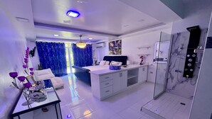 A modern hotel room with a large bed, a sitting area, a kitchenette, and a bathroom with a shower. - Family Friendly~Chef Service- Book 8 to 14 Rooms (Sosua)