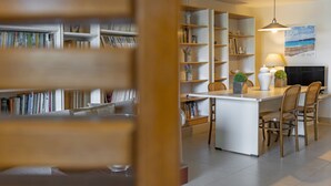 Un salon moderne doté d’un îlot central, de bibliothèques et d’une cheminée.
