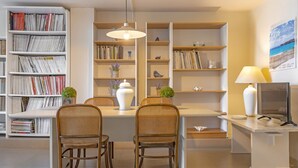 Une bibliothèque moderne avec des étagères, une table à manger avec des chaises et un téléviseur.